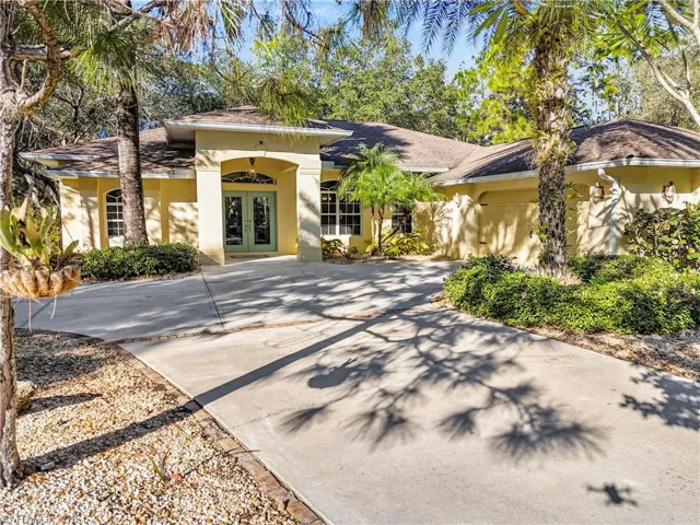 View of front facade with french doors, driveway, and stucco siding