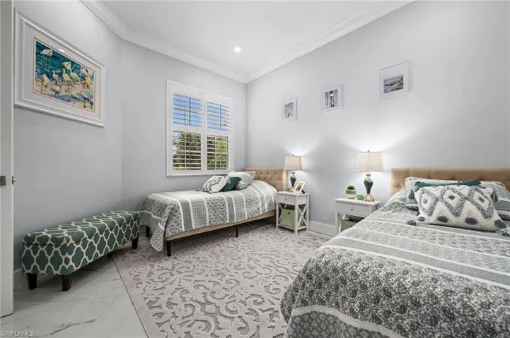 Bedroom with ornamental molding, light marble finish floors, and recessed lighting