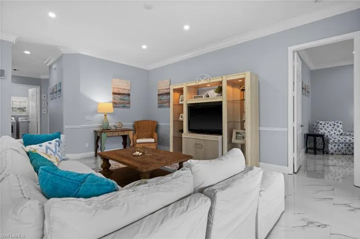 Living room featuring crown molding, recessed lighting, and marble finish flooring