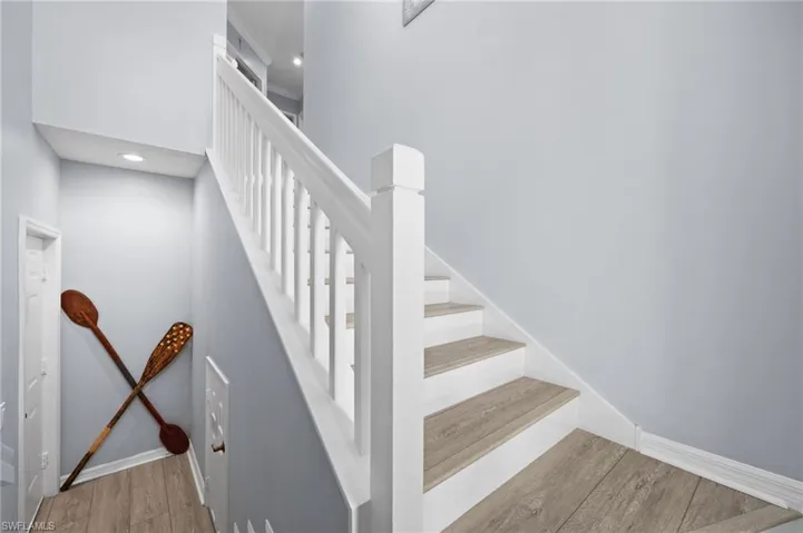 Stairway with wood finished floors, recessed lighting, and a high ceiling