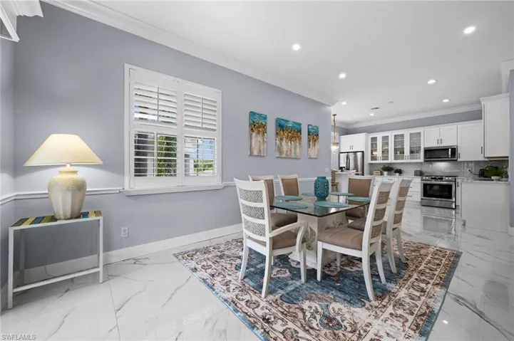 Dining space featuring crown molding, recessed lighting, and light marble finish flooring