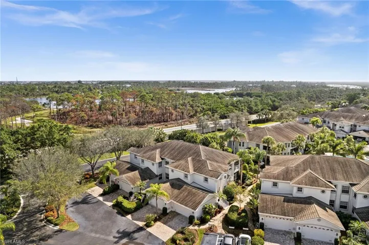 Aerial view of residential area with a large body of water and a tree filled landscape
