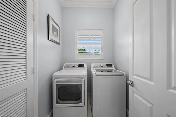 Laundry room with washer and clothes dryer and crown molding
