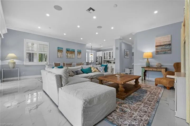 Living room with ornamental molding, recessed lighting, and light marble finish floors