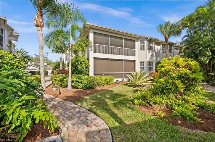Back of property with a sunroom, stucco siding, and a lawn