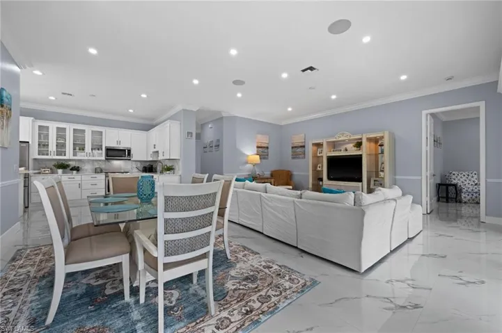 Living room featuring crown molding, light marble finish floors, and recessed lighting