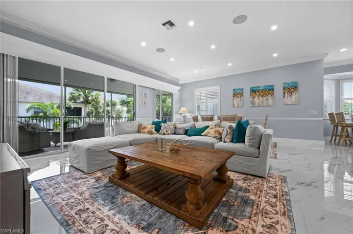 Living room with light marble finish floors, ornamental molding, and recessed lighting