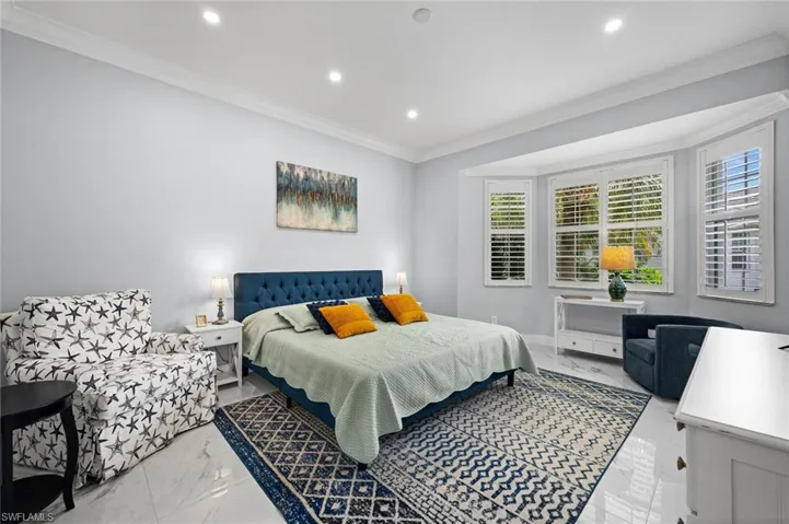 Bedroom with light marble finish floors, crown molding, and recessed lighting