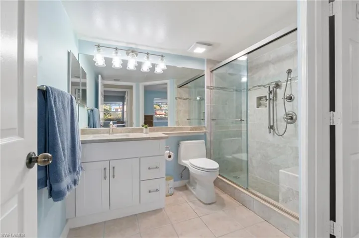 Full bathroom with a stall shower, vanity, toilet, and tile patterned floors