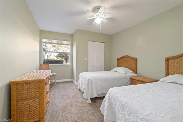 Carpeted bedroom with ceiling fan, a closet, baseboards, and a textured ceiling