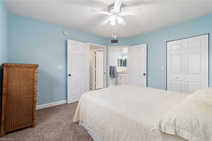 Carpeted bedroom featuring baseboards, visible vents, a ceiling fan, a textured ceiling, and a closet