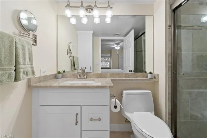 Bathroom featuring visible vents, toilet, ceiling fan, a shower stall, and vanity
