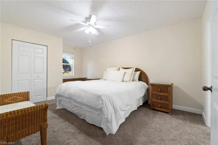 Carpeted bedroom with a textured ceiling, ceiling fan, a closet, and baseboards