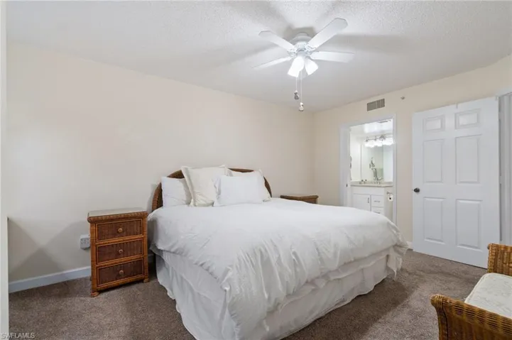 Bedroom with a textured ceiling, carpet floors, visible vents, and baseboards