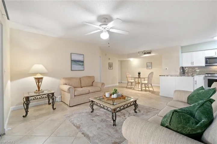 Living area featuring a textured ceiling, light tile patterned flooring, and baseboards