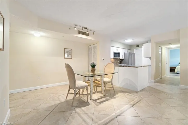 Dining area featuring light tile patterned floors, visible vents, baseboards, and a textured ceiling