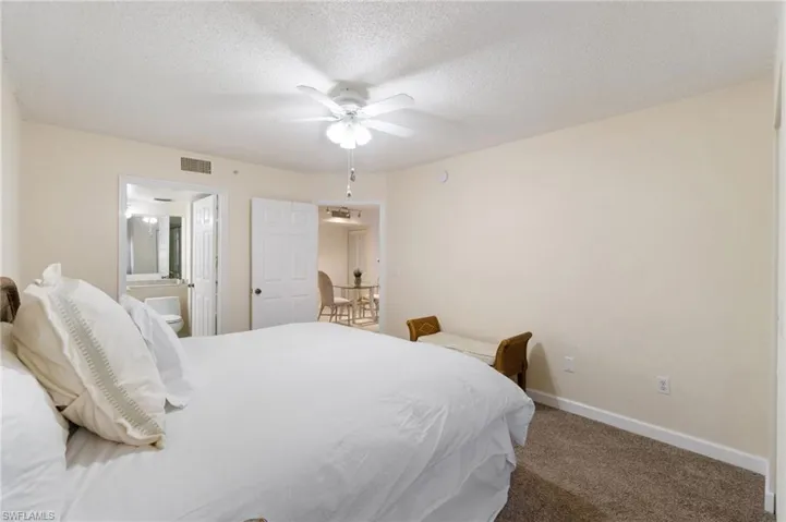 Bedroom with a textured ceiling, carpet floors, visible vents, and baseboards
