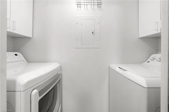 Laundry area with independent washer and dryer, cabinet space, and electric panel
