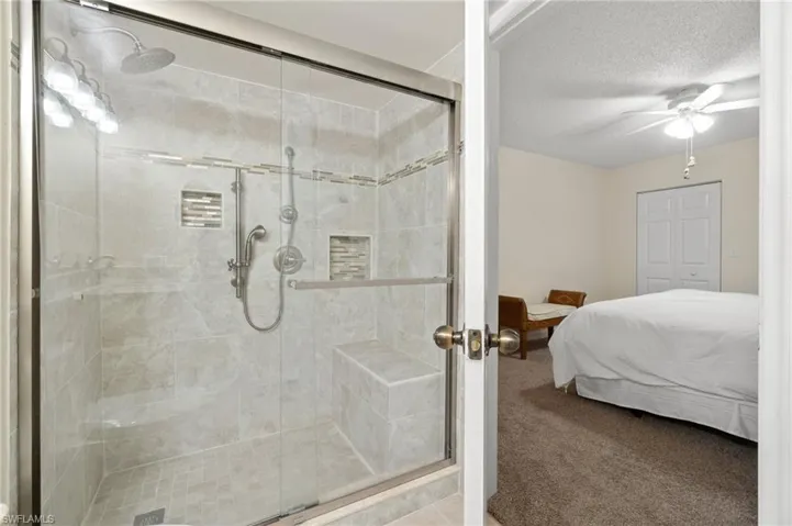 Ensuite bathroom featuring a shower stall, ceiling fan, a textured ceiling, and ensuite bathroom