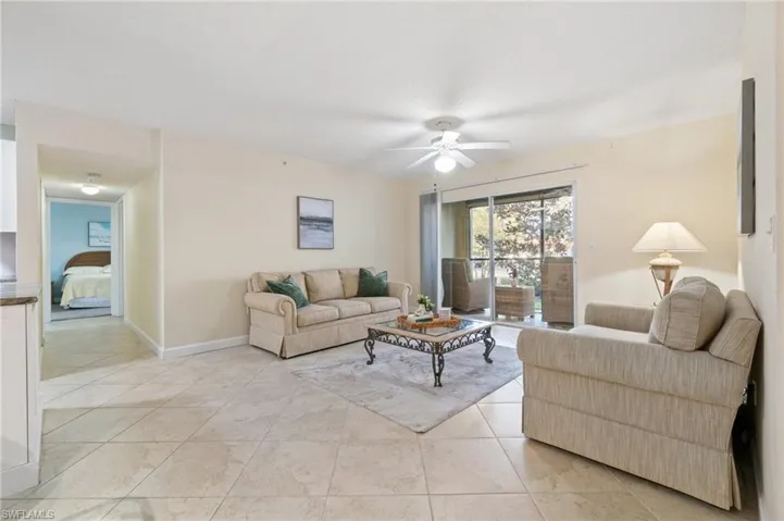 Living room with a ceiling fan, light tile patterned flooring, and baseboards
