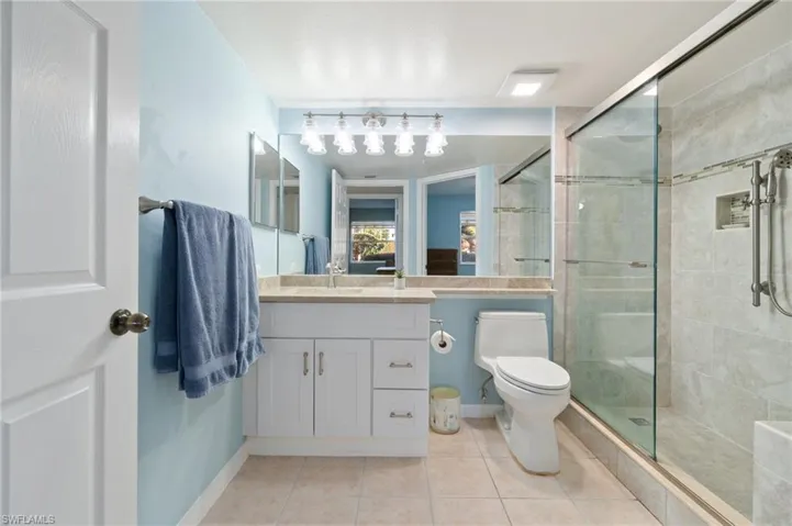 Full bath with tile patterned flooring, toilet, vanity, baseboards, and a stall shower