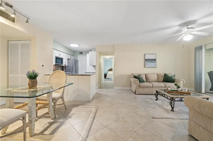 Living area with light tile patterned floors, baseboards, visible vents, ceiling fan, and a textured ceiling