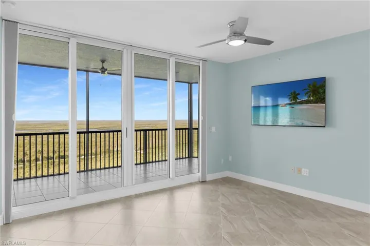 Unfurnished room featuring a wall of windows and a ceiling fan