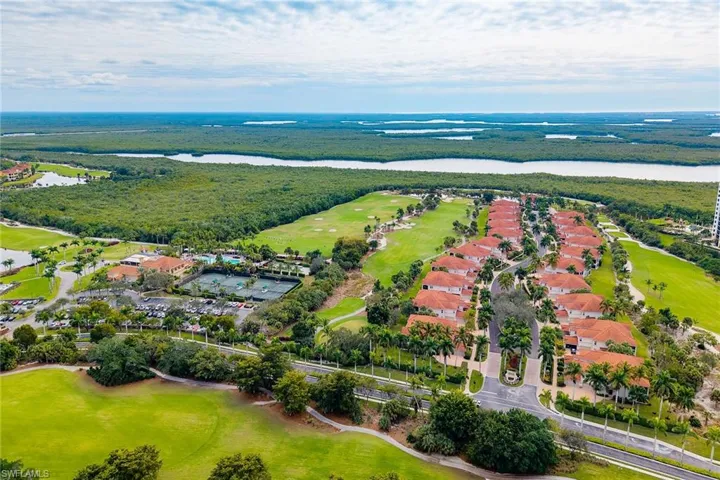 Aerial view of property and surrounding area featuring a golf club, a nearby body of water, and nearby suburban area