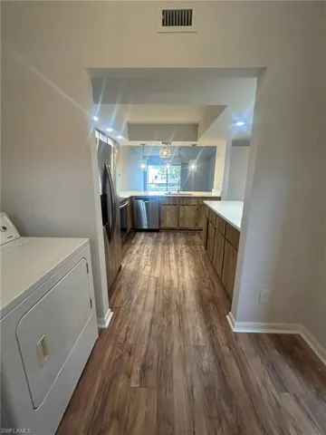 Kitchen featuring dark wood-style flooring, light countertops, visible vents, washer / clothes dryer, and appliances with stainless steel finishes