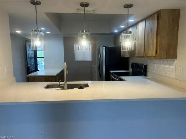 Kitchen featuring light countertops, a sink, a raised ceiling, tasteful backsplash, and electric range