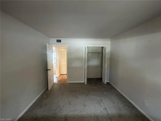 Unfurnished bedroom with carpet flooring, baseboards, a closet, and visible vents