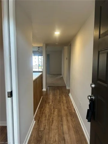 Corridor with dark wood-style flooring and baseboards