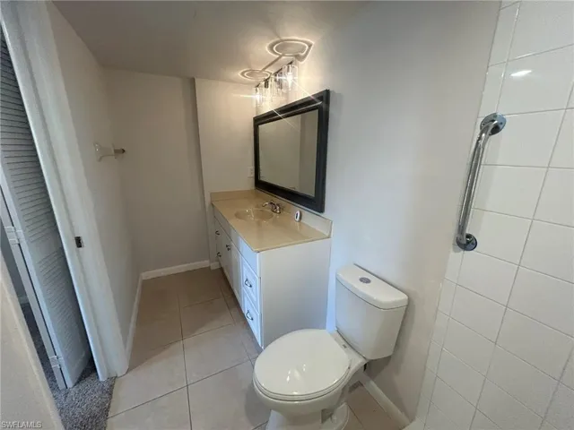 Bathroom featuring toilet, vanity, baseboards, and tile patterned flooring