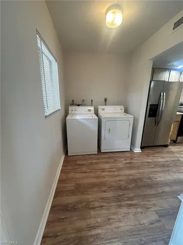 Clothes washing area featuring visible vents, wood finished floors, washing machine and clothes dryer, and laundry area