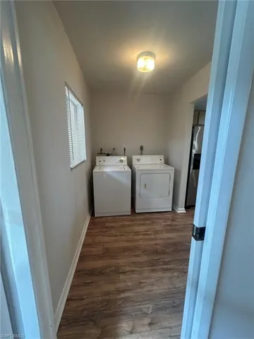 Clothes washing area featuring washing machine and dryer, baseboards, laundry area, and dark wood finished floors