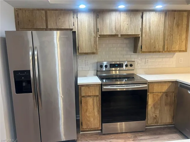 Kitchen with wood finished floors, light countertops, tasteful backsplash, and stainless steel appliances