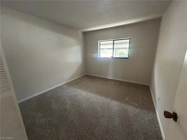 Carpeted empty room featuring baseboards