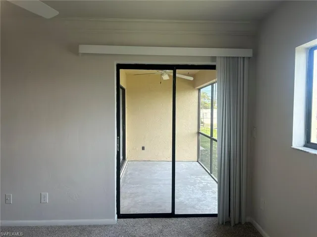 Empty room with carpet floors, ornamental molding, baseboards, ceiling fan, and a textured wall