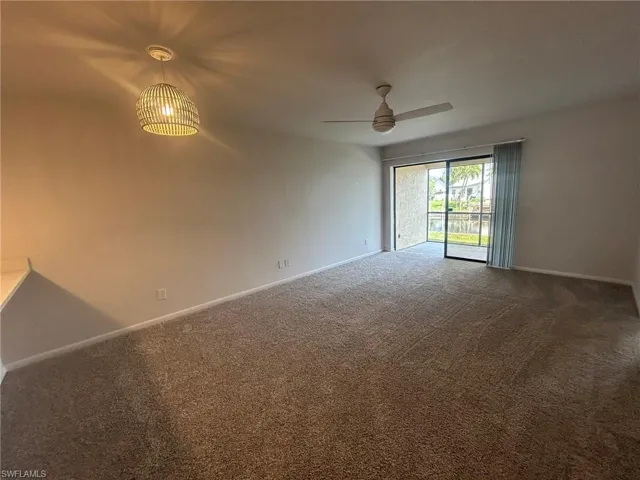 Carpeted spare room with baseboards and ceiling fan
