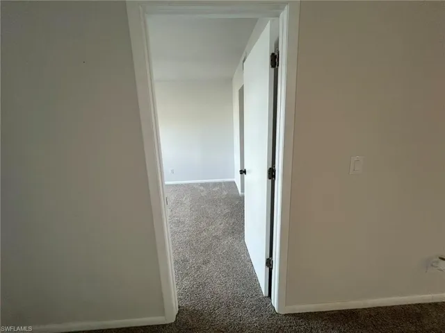 Hallway featuring carpet flooring and baseboards