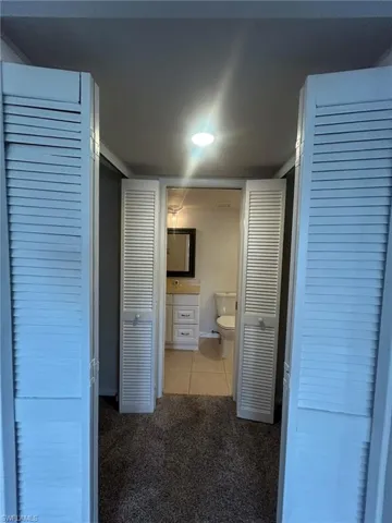 Hallway featuring tile patterned flooring and carpet