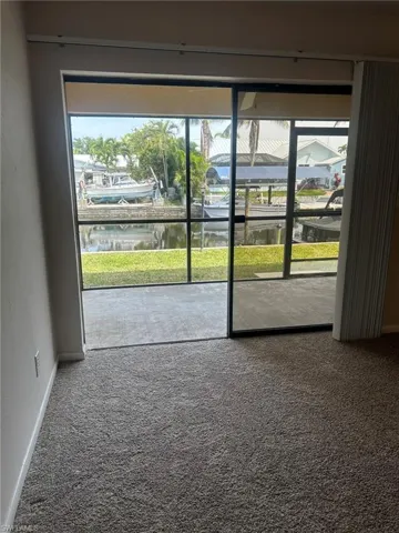 Empty room featuring baseboards, a water view, and carpet flooring