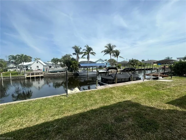Dock area featuring boat lift, a residential view, a water view, and a yard