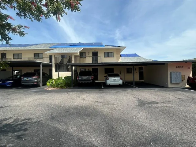 View of front of property featuring covered parking, solar panels, and stucco siding