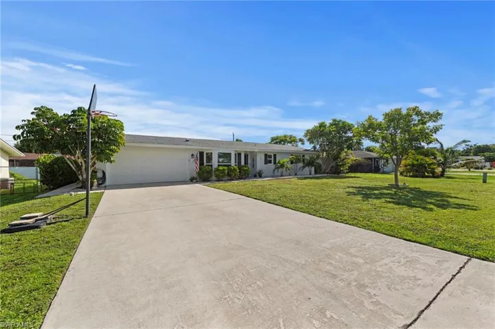 Single-story residence featuring a two-car garage, concrete driveway, and a front yard with mature landscaping