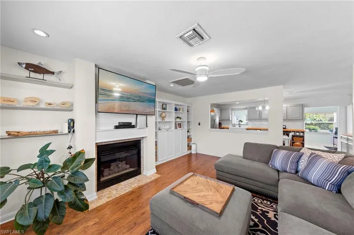 Recessed lighting, wood-finish flooring, built-in shelving, and a gas fireplace with a tiled hearth