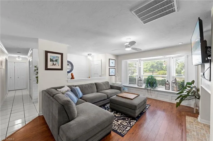 Living area featuring wood-finish flooring, a bay window with a built-in window seat, a ceiling fan, and recessed lighting