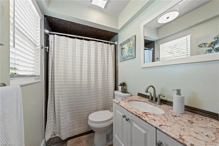 White shaker-style vanity with a granite countertop and undermount sink