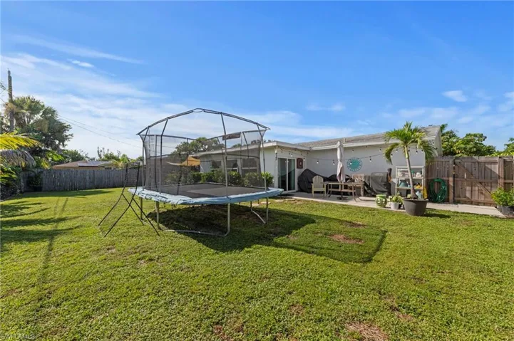 Expansive grassy yard area with mature perimeter landscaping and a privacy fence