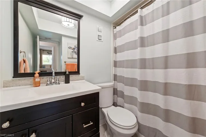 Vanity with a white countertop and integrated sink, chrome faucet, and dark wood cabinetry